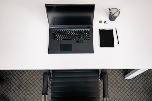 Top View of a Contemporary Neat Desk with a Laptop, Notepad and Writing Supplies 