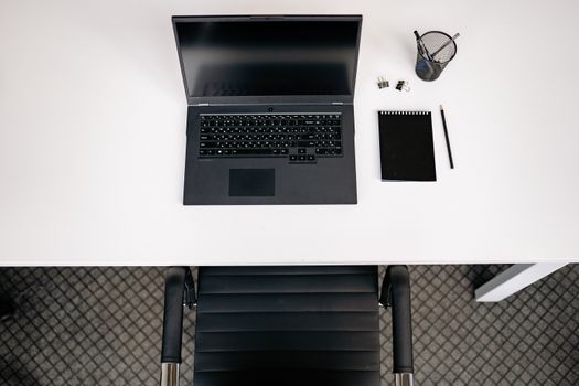 Top view of a minimalist office desk setup with laptop, notepad, and stationery.