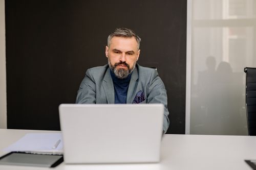 Free Middle-aged professional man concentrating on his work using a laptop in an office environment. Stock Photo