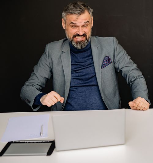 Free Businessman showing frustration while looking at laptop in office setting. Stock Photo