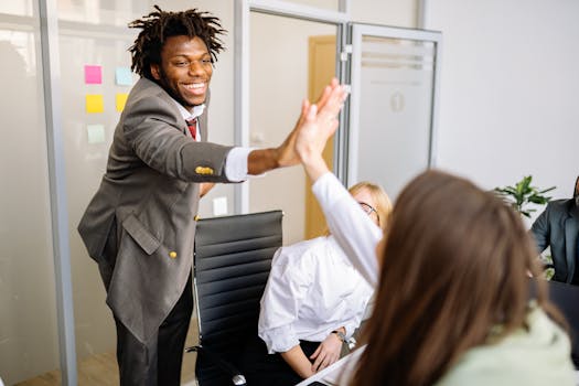 Diverse colleagues celebrating success with a high five in a modern office.