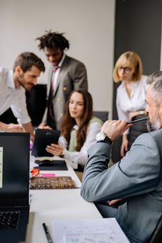 Group of professionals collaborating in a modern office, focusing on teamwork and diversity.