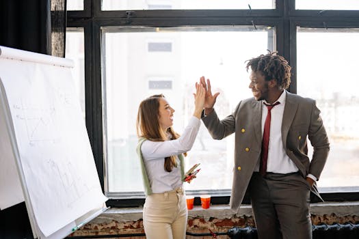 A business team high-fiving in an office, celebrating a successful presentation.