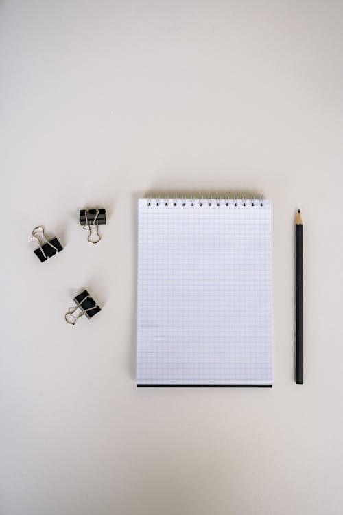 White Graphing Paper Beside Black and Silver Paper Clip