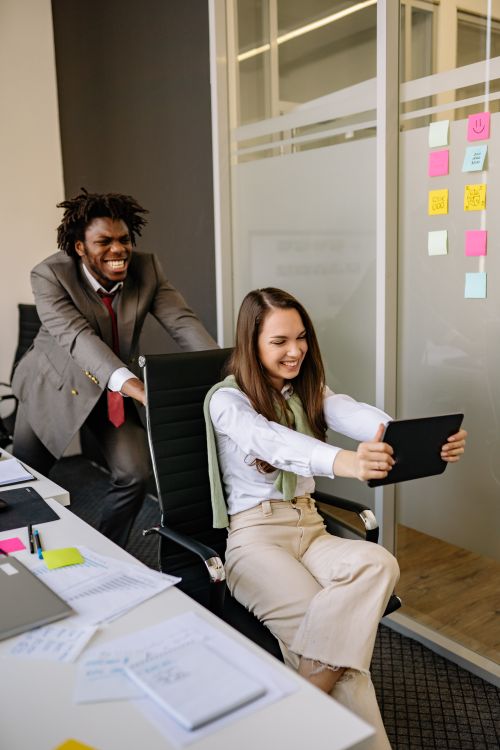 Free Diverse colleagues playfully interact in an office setting, boosting team spirit. Stock Photo