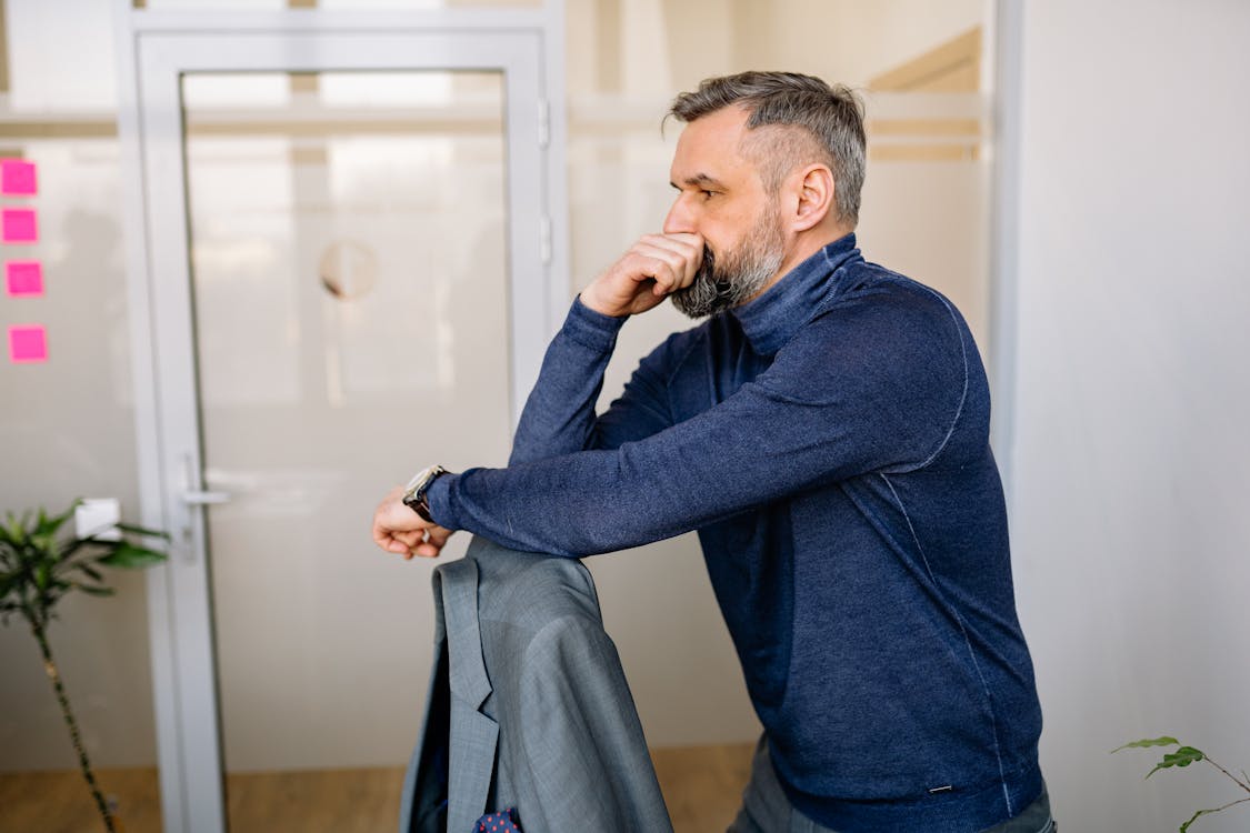 Man in Blue Long Sleeve Shirt Standing Near Doorway