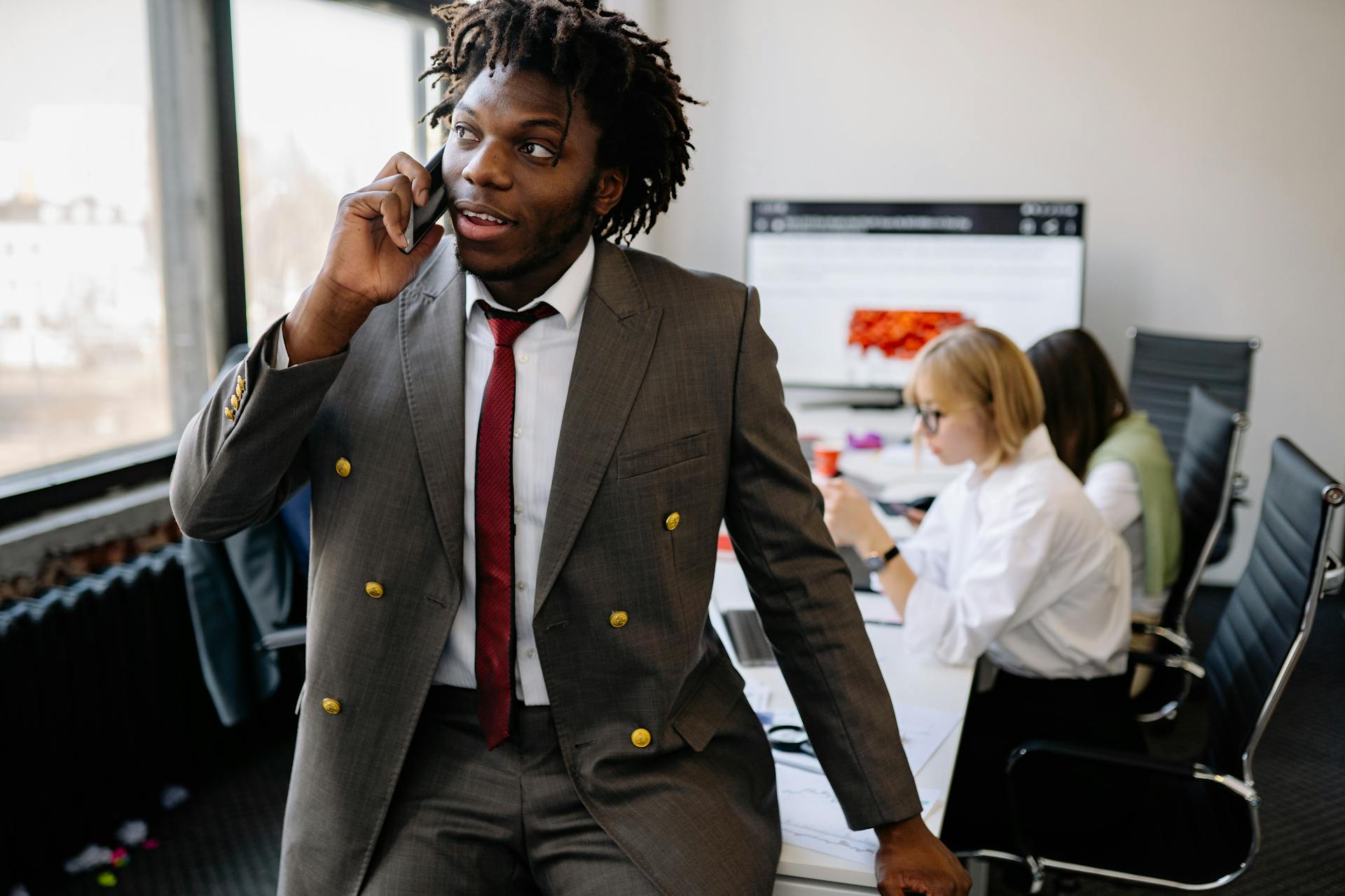 Professional young businessman talking on a phone in a modern office setting.