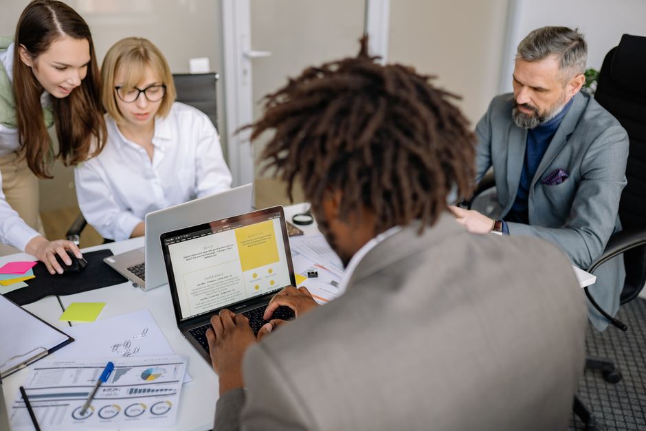 Diverse team working together on a project in an office with laptops and charts.