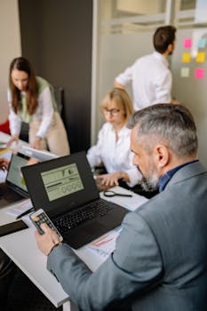 Corporate team working together with technology in a modern office setting, promoting collaboration and productivity.