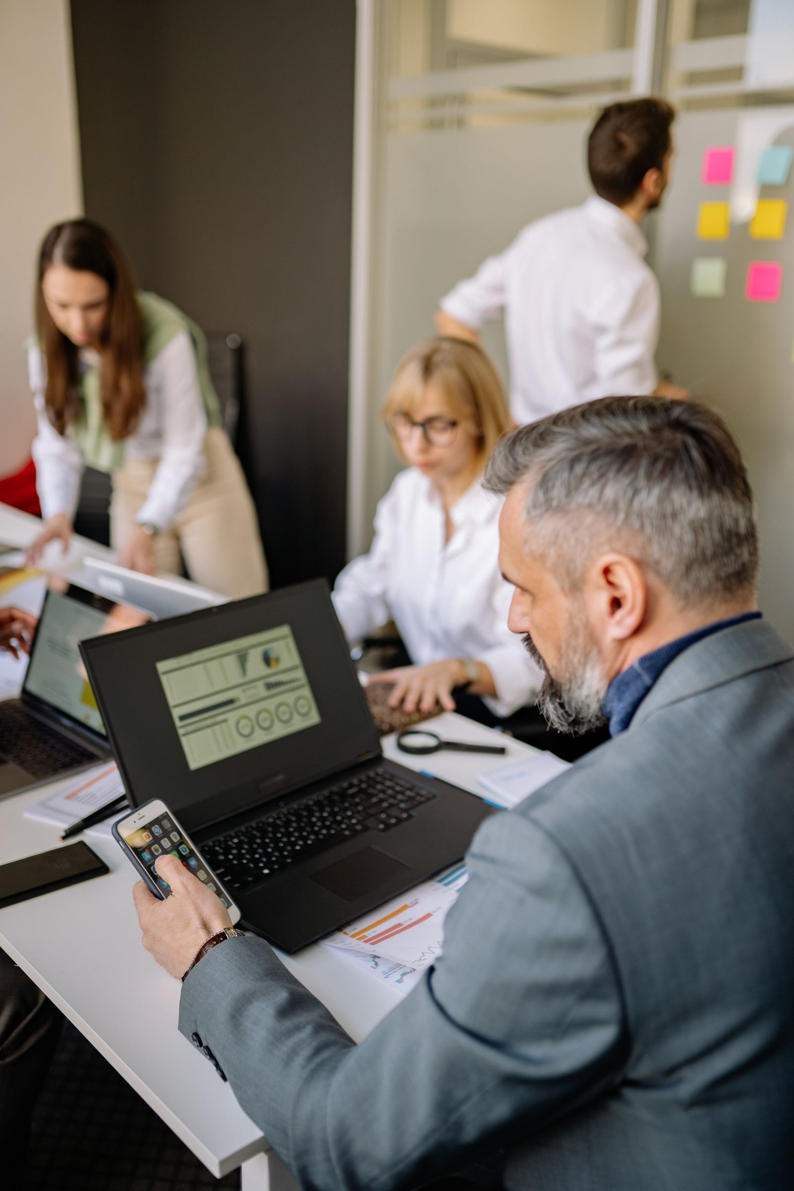 Equipe corporativa reunida com smartphone e notebook para planejamento de soluções