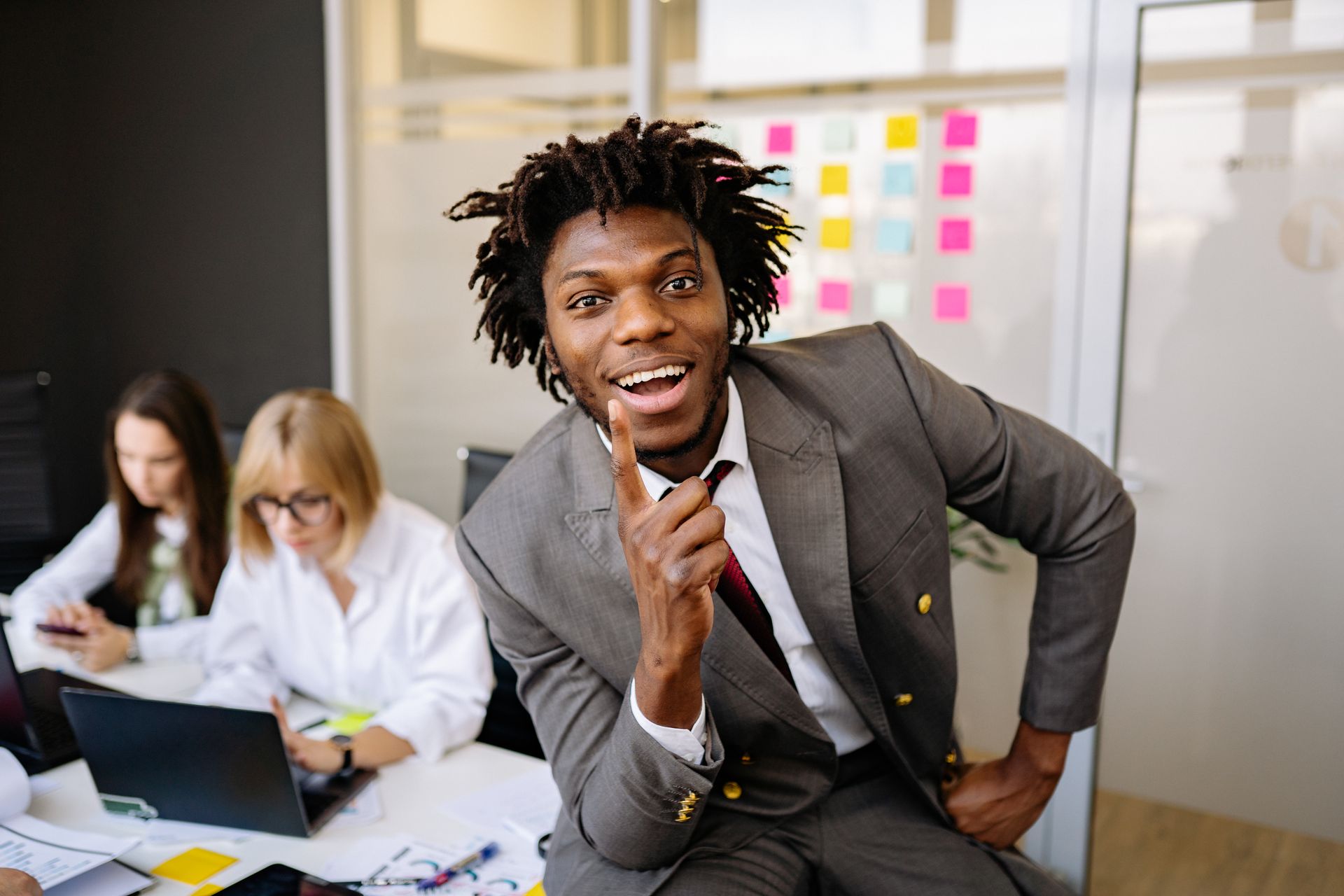 Smiling young man in suit posing in a busy office environment.