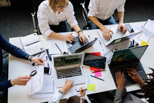 Overhead view of a corporate team collaborating with laptops and documents.