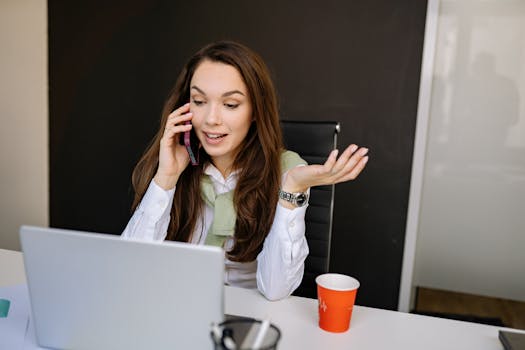 Young businesswoman smiling while talking on the phone in a modern office setting.