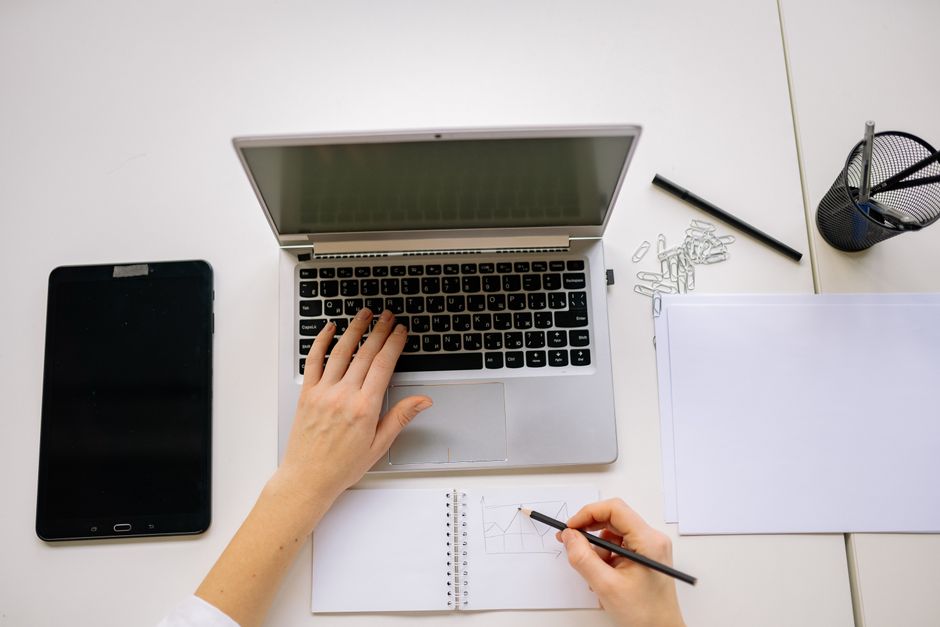 Photo by Yan Krukau on Pexels Hands multitasking on laptop and notepad with tablet on desk, perfect for productivity themes.