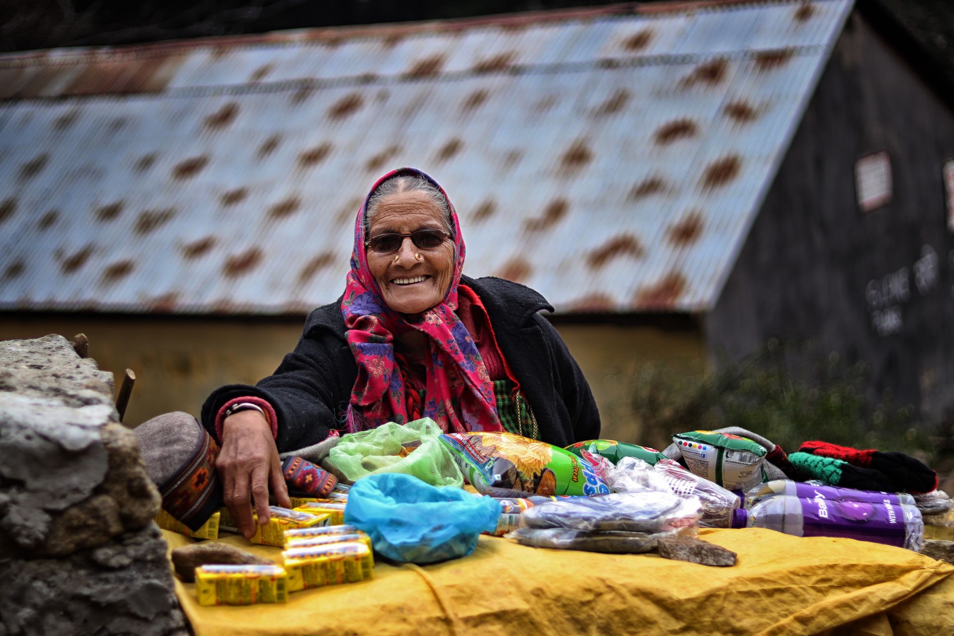 Charming senior woman selling traditional goods in Manali, India market.