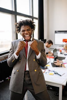 Excited African American businessman celebrating success with joy in an office setting.
