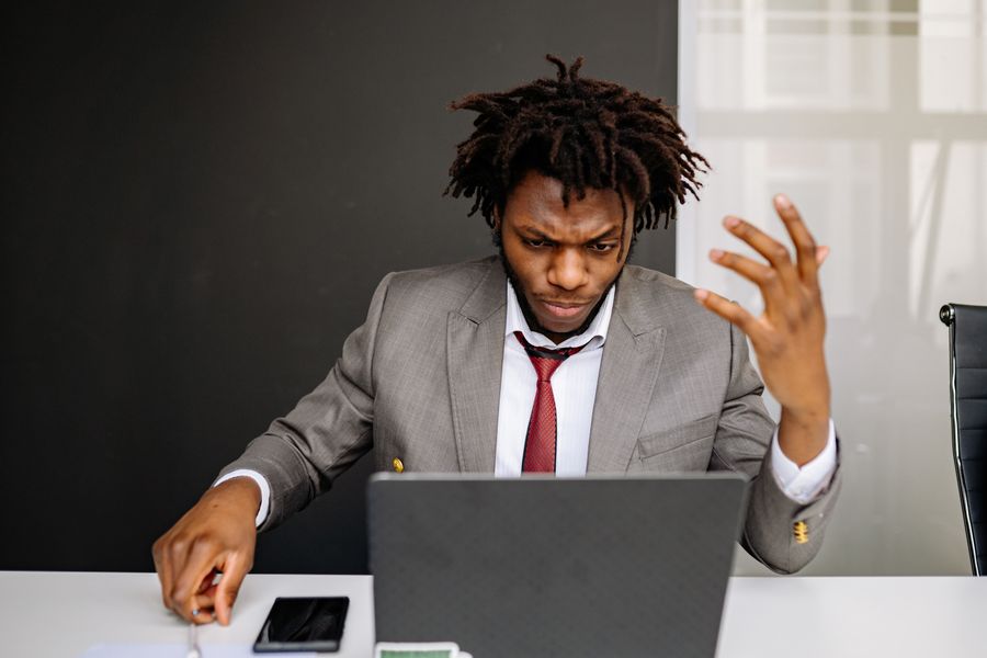 Businessman in a suit frustrated while working on a laptop at his desk.