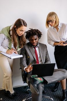 Diverse group of professionals teaming up for a project discussion around a laptop.