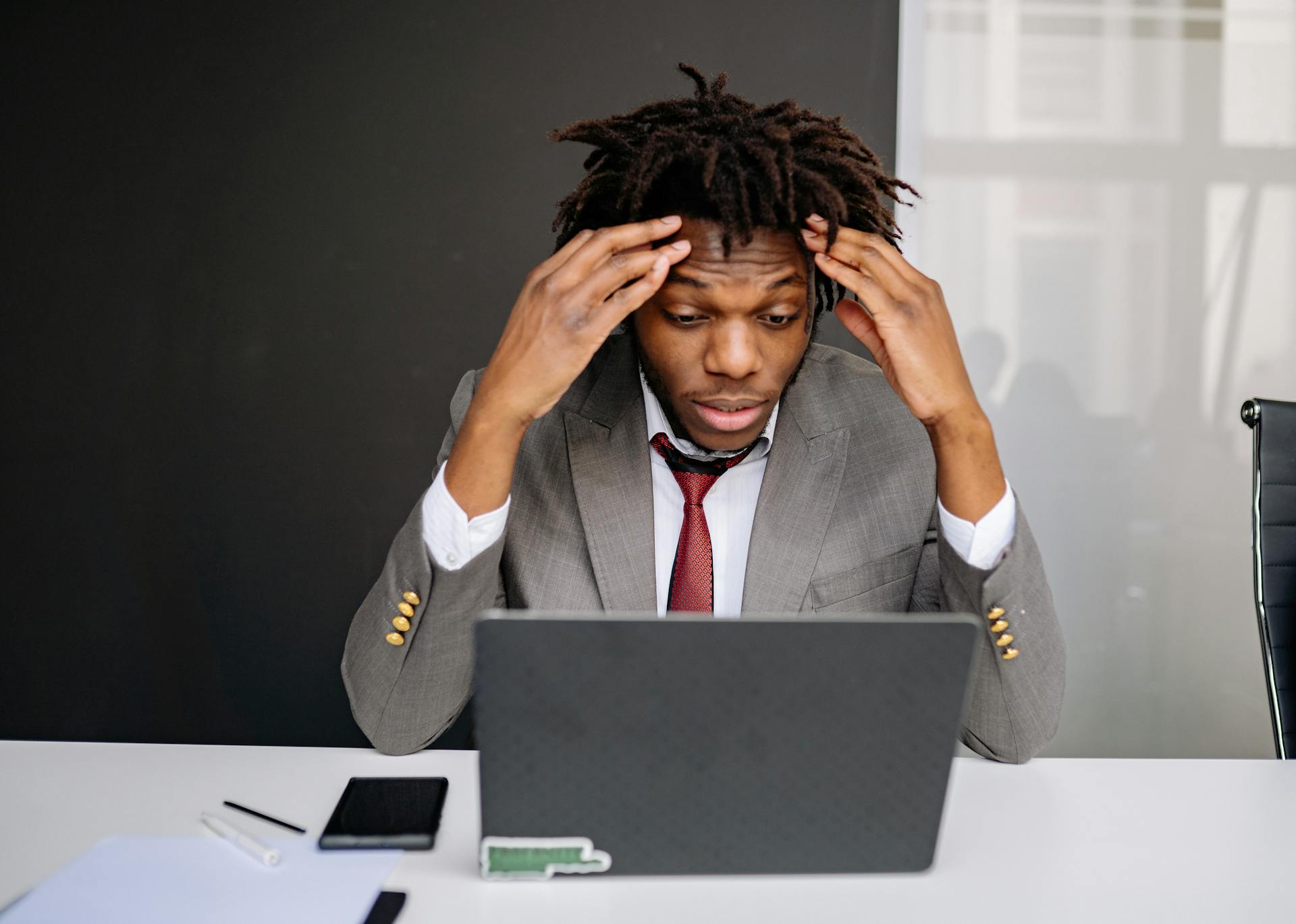 African American businessman experiencing stress while working on a laptop indoors.