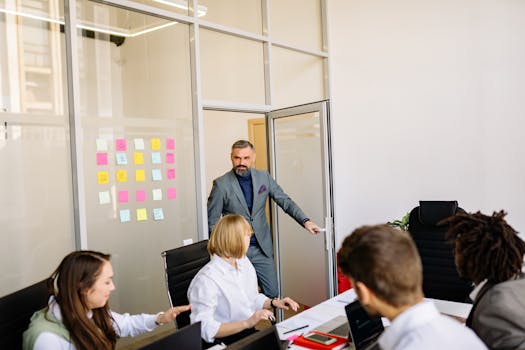 Business team collaborating in a conference room with post-it notes on a glass door.