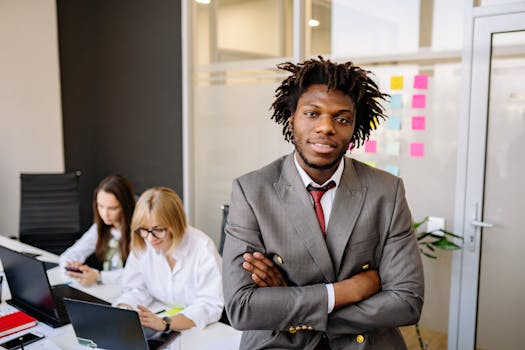 Professional business leader posing confidently in a modern office with team.