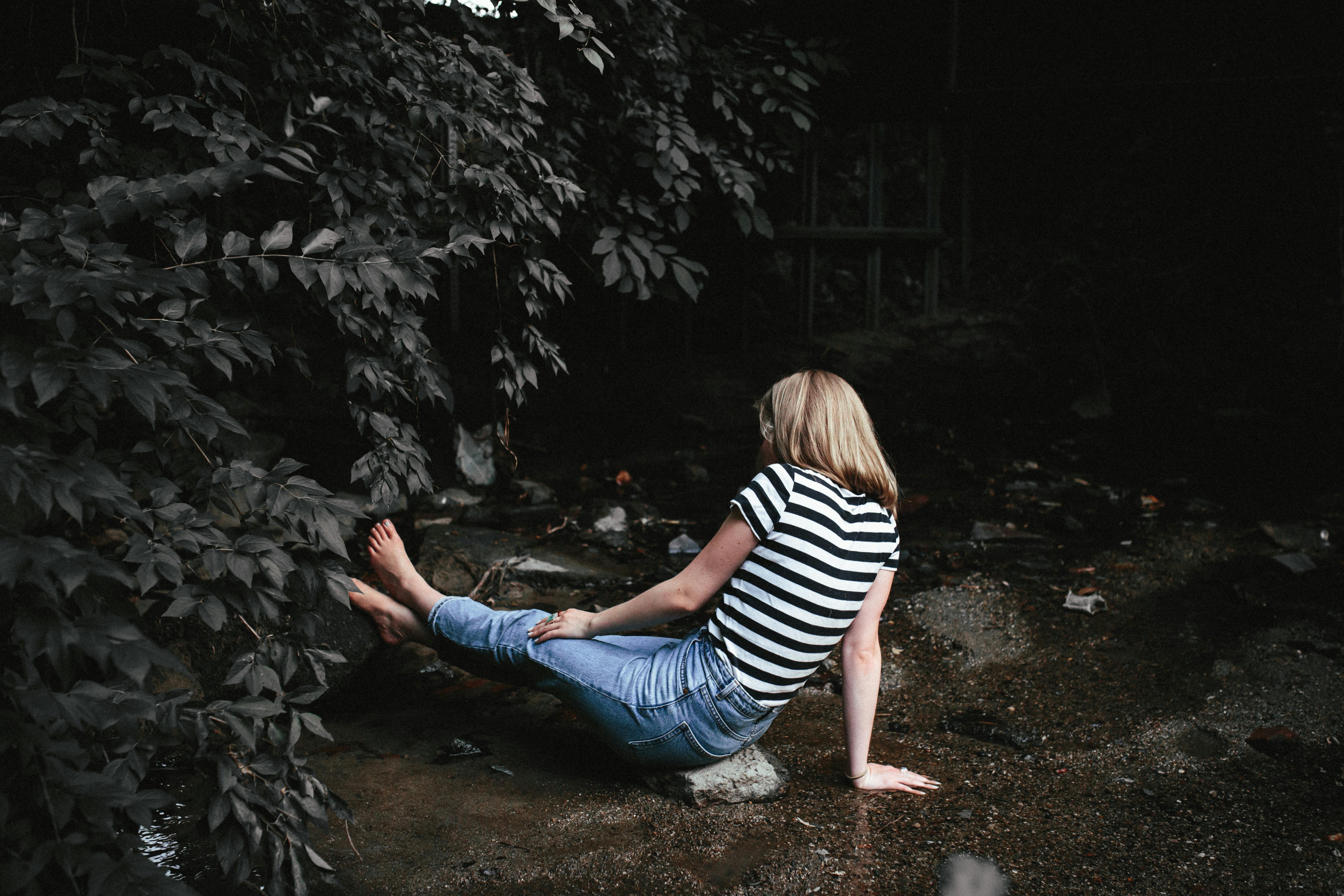 Blonde woman sitting by a stream in Greensboro, North Carolina wilderness.