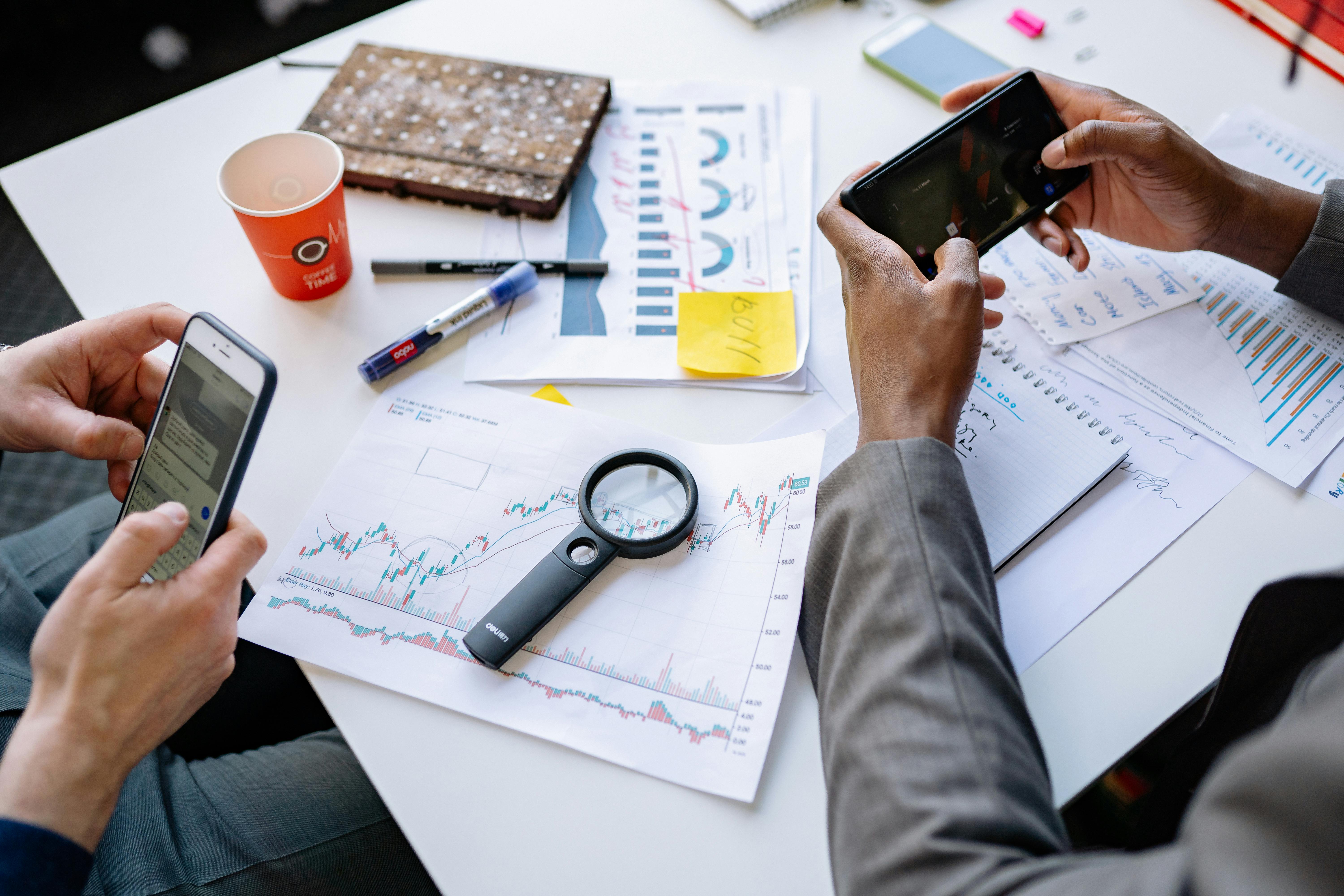 people using smartphones near paperwork on white table