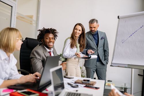 Free Business team collaborating during a meeting in a modern office space with charts. Stock Photo