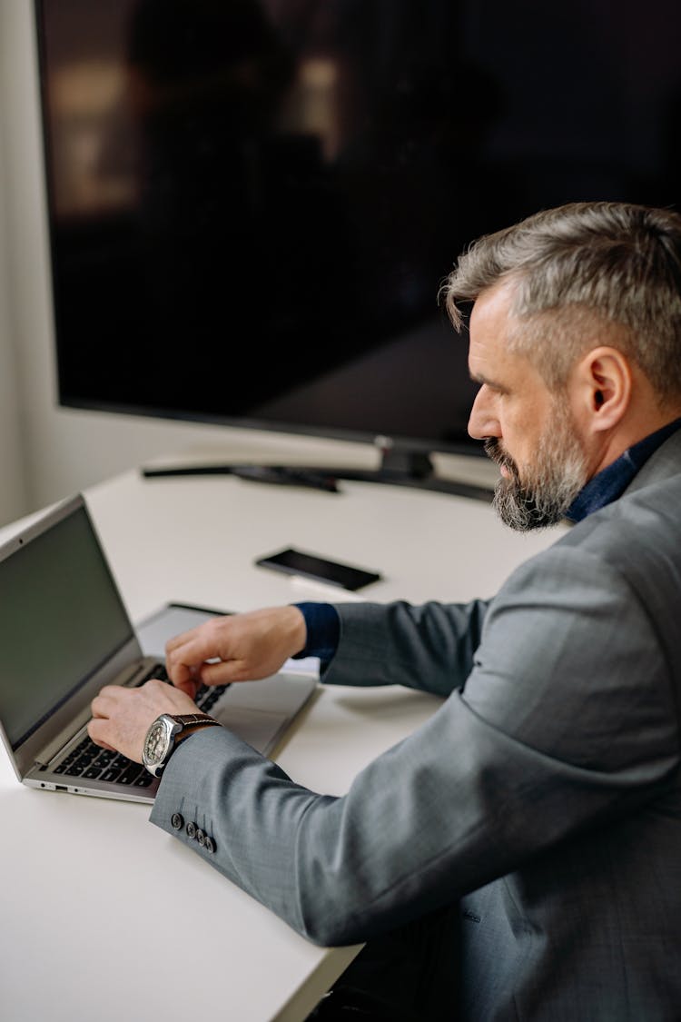 A Bearded Man In A Suit Using His Laptop