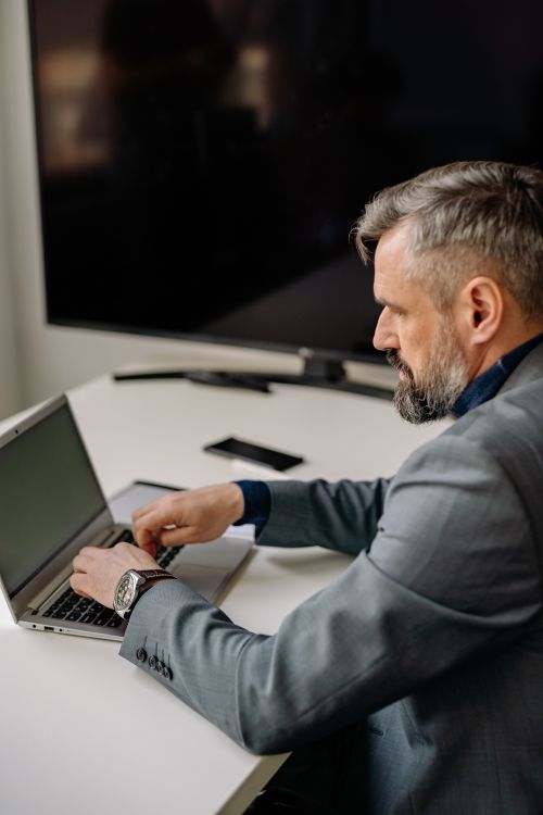 Free Focused adult businessman typing on a laptop at an office desk. Stock Photo