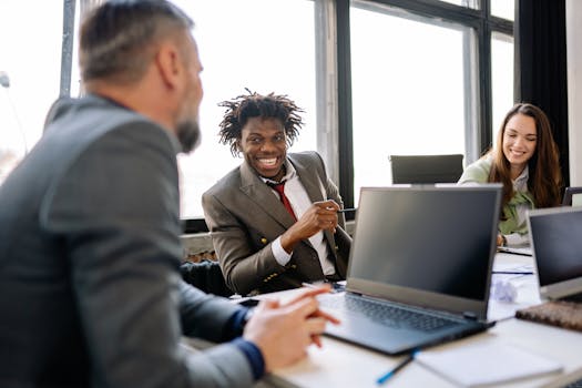 A diverse group of colleagues brainstorming and smiling in a bright office environment.