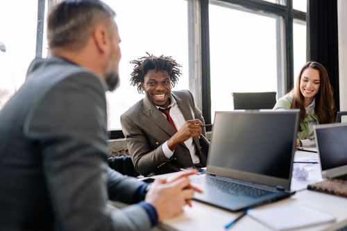 Free A diverse group of colleagues brainstorming and smiling in a bright office environment. Stock Photo