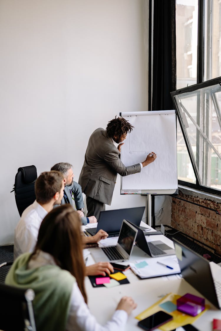 A Man In Gray Suit Writing On A Whiteboard