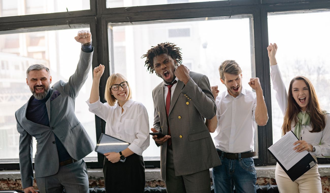 Team celebrating with raised fists in a bright office — photo by Yan Krukau on Pexels
