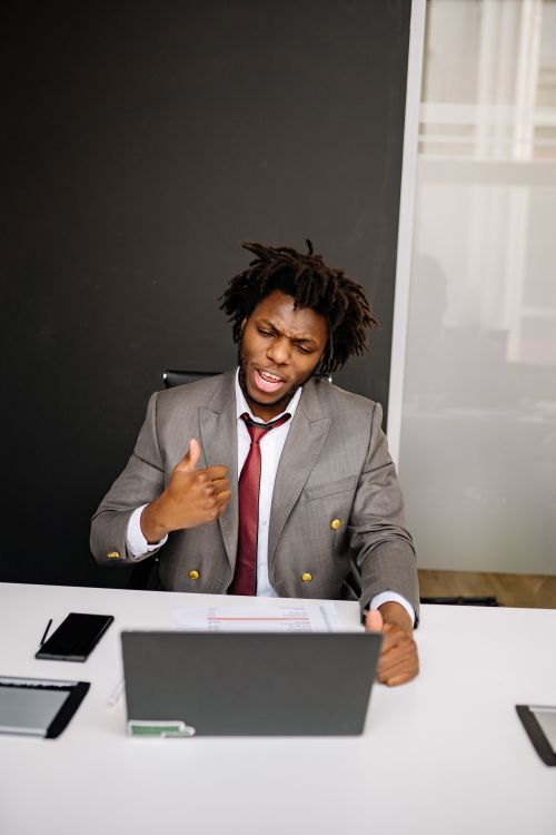 Free Confident professional giving thumbs up while video conferencing at work desk. Stock Photo