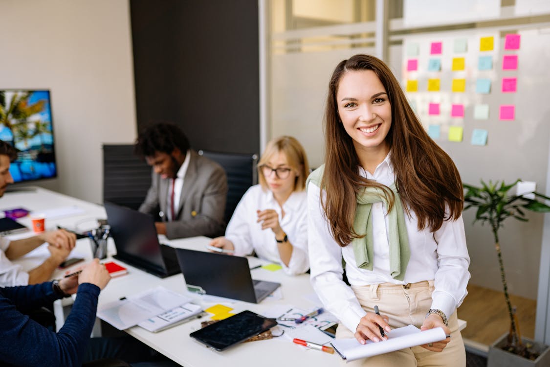Free An Employee Sitting on a Table while Smiling at the Camera Stock Photo