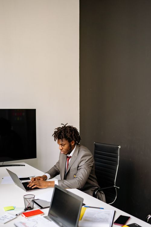 Free Professional businessman working intently on a laptop in a modern office setting. Stock Photo