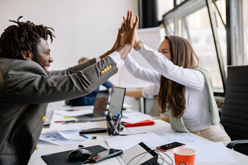 Free Woman and a Man Doing High Five at the Office Stock Photo
