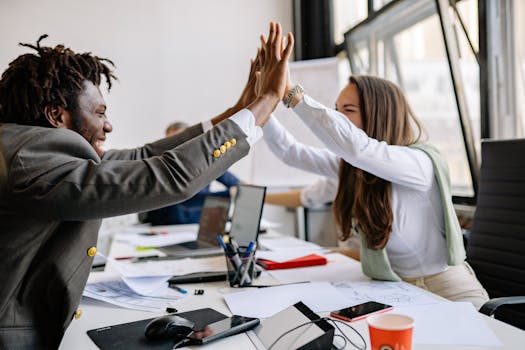 Multiracial colleagues celebrating a successful meeting with a high five in a modern office setting.