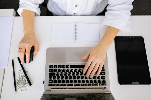 Top view of an office workspace with a laptop, tablet, and hands typing. Ideal for business and technology themes.