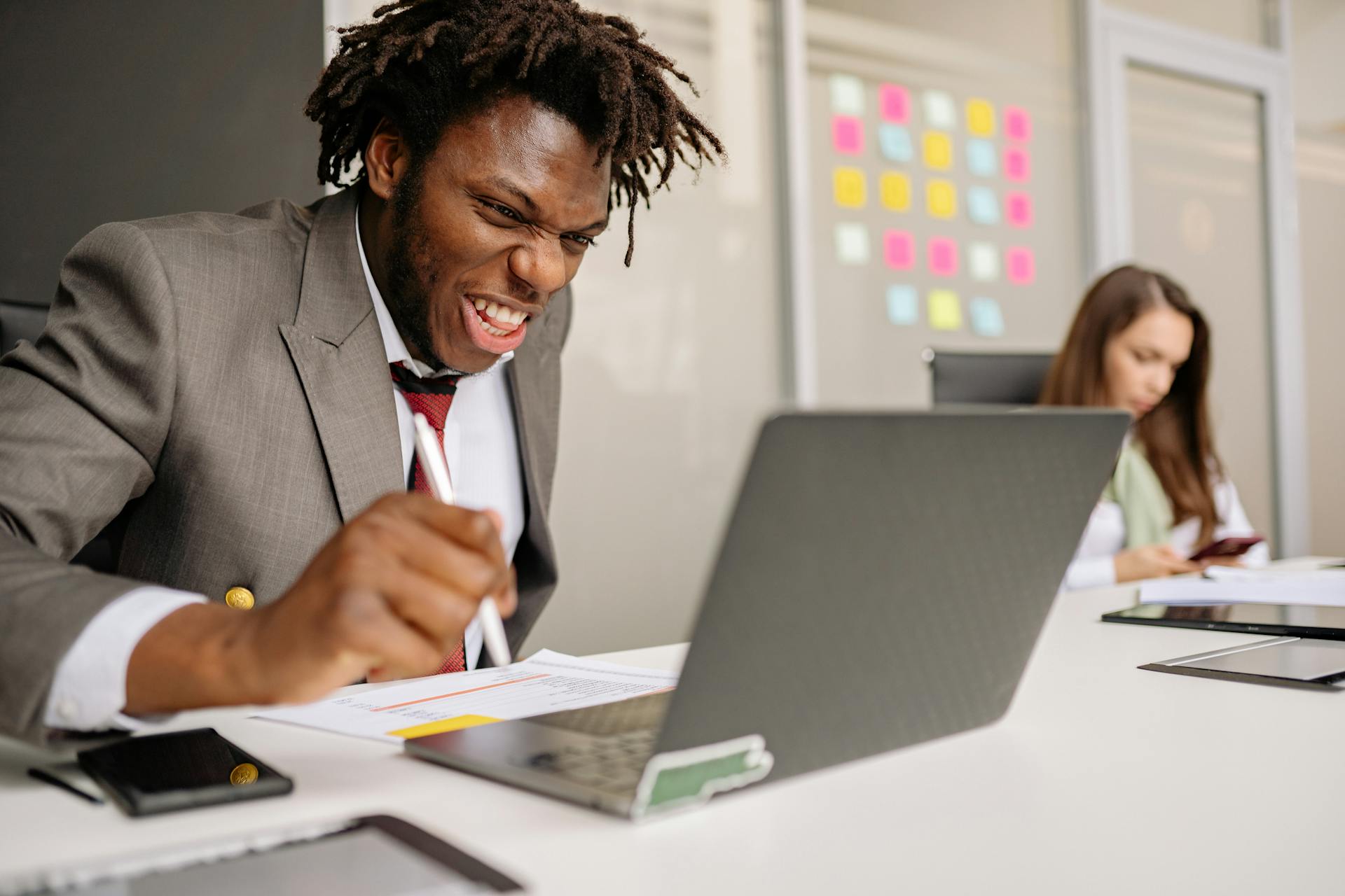 Businessman enthusiastically celebrating success in an office setting with a laptop.