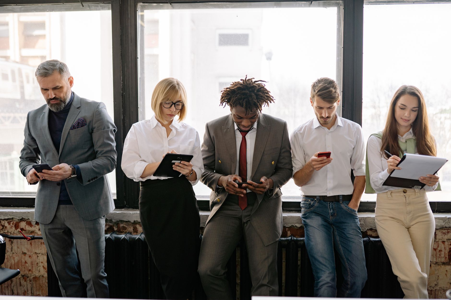 A diverse group of colleagues using mobile devices in an office setting.