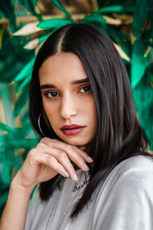 Free Close-up portrait of a woman with lush green background, captured in Hyderabad. Stock Photo