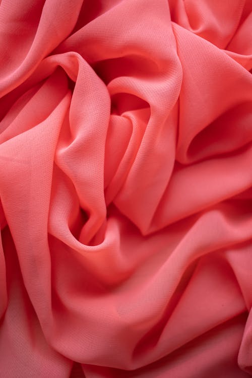 Background of from above of bright light pink satin uneven wrinkled textile with soft texture