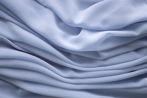 Closeup of textured background of crumpled light blue dyed textile with uneven texture
