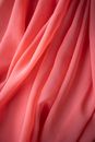 Abstract background of crumpled thin light pink textile with uneven surface and gentle texture