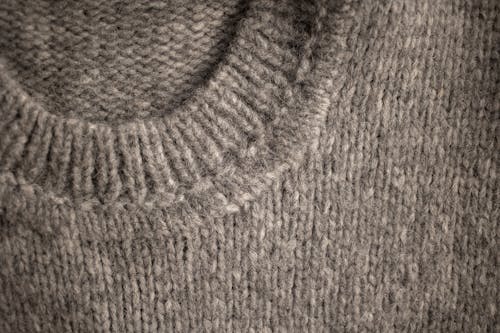 From above of textured backdrop representing warm woolen knitted light gray sweater collar with soft and warm texture