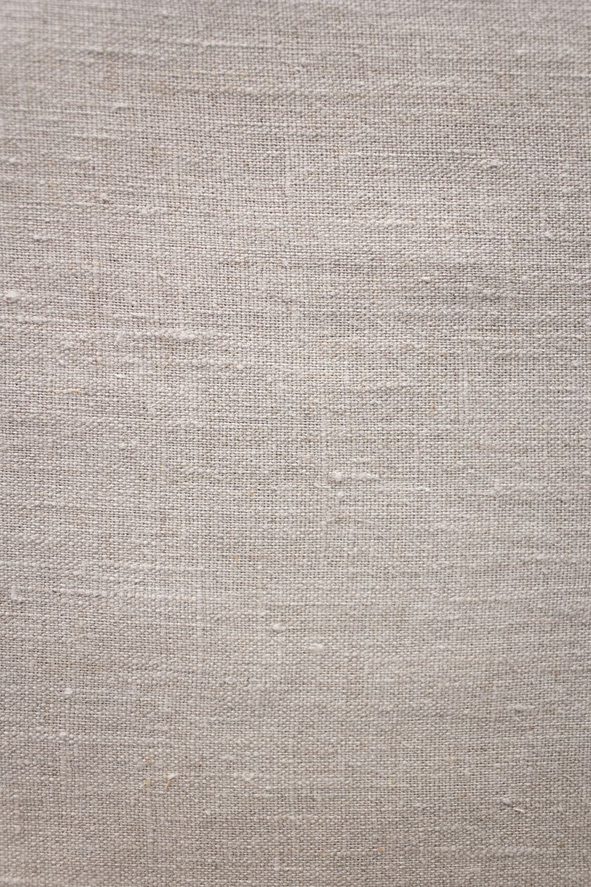 Close-up of a natural linen cloth, the uneven slubby yarns of the plain weave running across the frame.