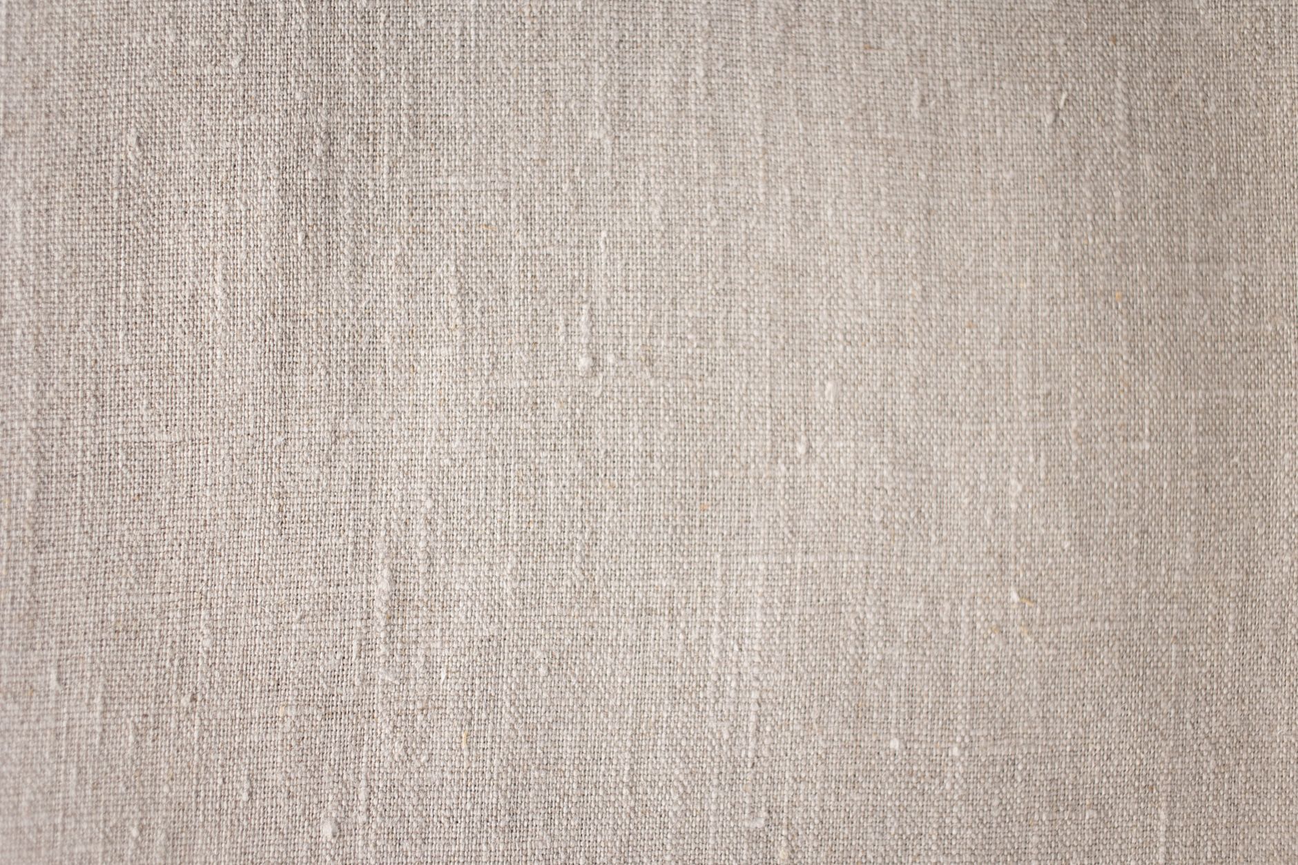 Detailed macro view of a neutral linen fabric surface showing texture and weave.