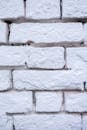 Background of textured shabby white wall made of rough bricks with uneven surface